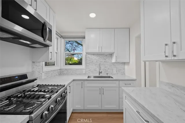 a kitchen with stainless steel appliances a sink a stove and microwave