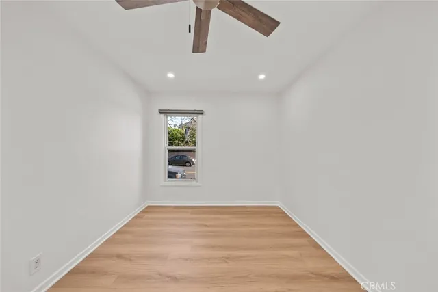 a view of empty room with wooden floor and ceiling fan