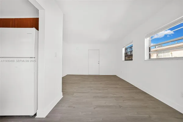 a view of an empty room with window and wooden floor