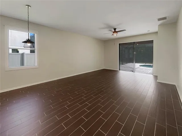 a view of a room with wooden floor and a ceiling fan