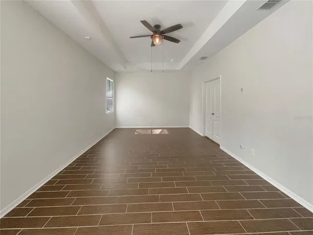an empty room with white walls and ceiling fan