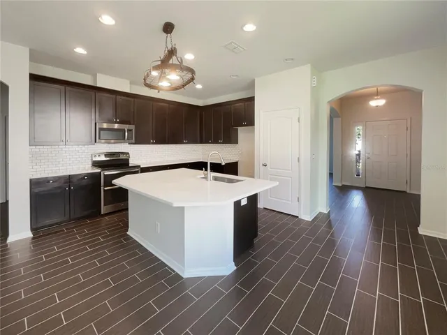 a kitchen with kitchen island stainless steel appliances a sink stove and refrigerator