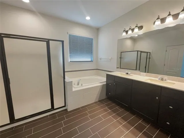 a bathroom with a double vanity sink a mirror and a bathtub