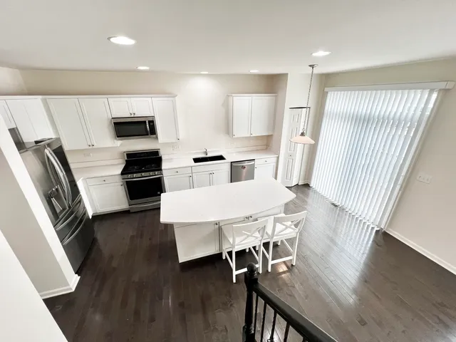 a kitchen with stainless steel appliances a table chairs refrigerator and microwave