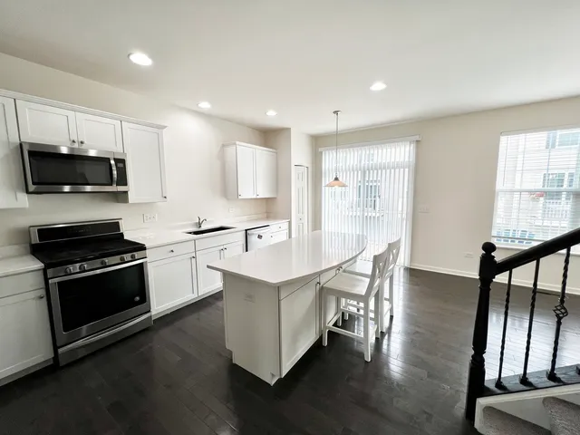 a kitchen with stainless steel appliances kitchen island granite countertop a stove a sink and a microwave