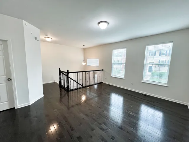 an entryway in wooden floor hall with windows and stairs