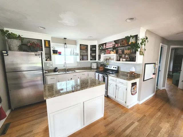 a kitchen with stainless steel appliances granite countertop a refrigerator a stove and a wooden floors