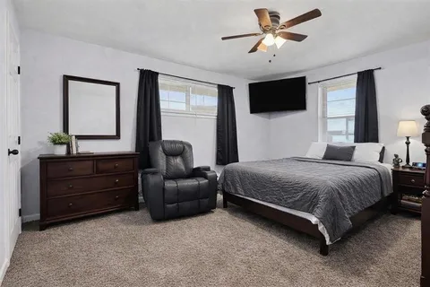 a bedroom with a bed and a flat tv screen on dresser