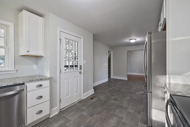 a view of kitchen with granite countertop cabinets and refrigerator