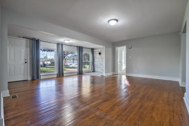 a view of an empty room with window and wooden floor