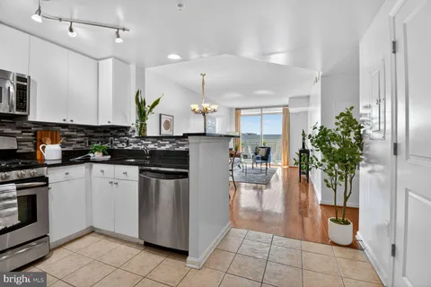 a kitchen with stainless steel appliances granite countertop a refrigerator a sink a stove and white cabinets