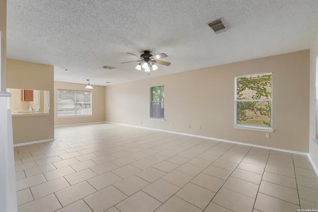 an empty room with windows and chandelier fan