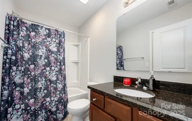 a bathroom with a granite countertop sink and a toilet