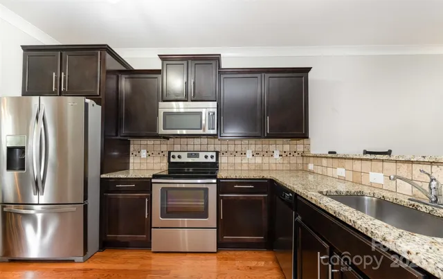 a kitchen with granite countertop a refrigerator stove and sink