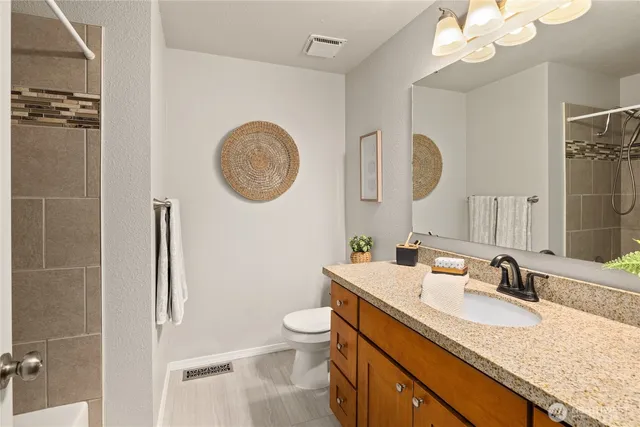 a bathroom with a granite countertop sink a toilet and a mirror