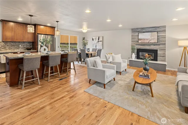 a living room with furniture a fireplace and a dining table with wooden floor