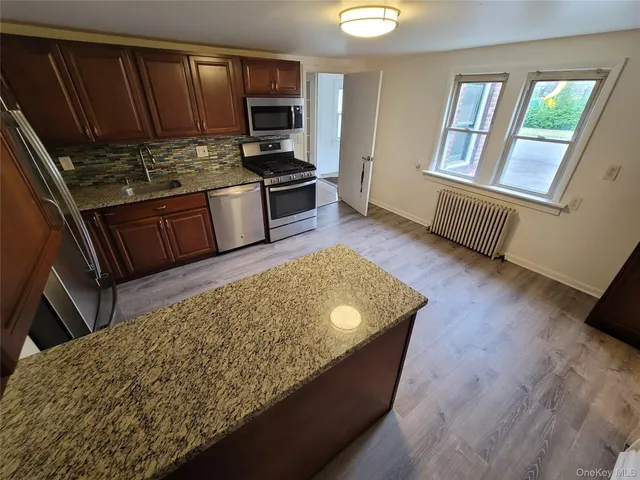 a living room with stainless steel appliances furniture a rug and a window