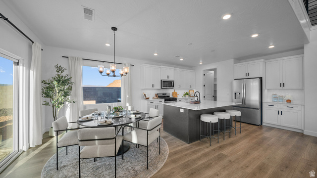 324 North Rhyolite Drive, Unit 87 Hurricane, UT 84737 - Photo 11 of 33 Kitchen with stainless steel appliances, an island with sink, a breakfast bar area, suspended lighting, and light stone counters