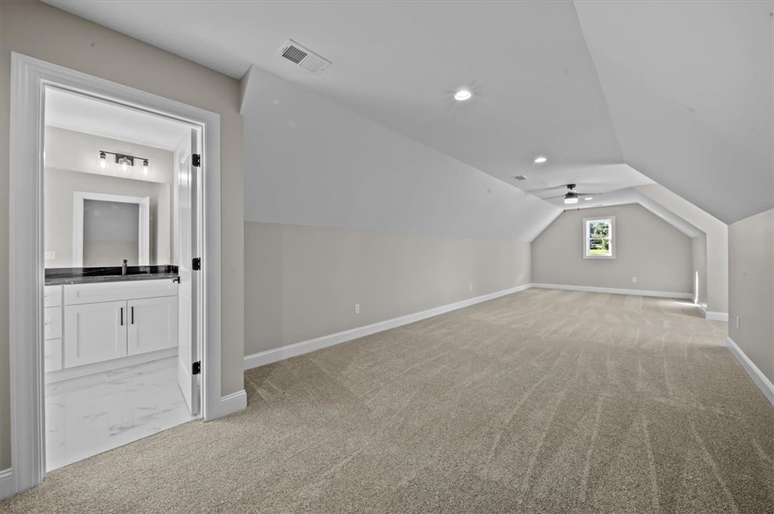 105 Bree Drive Anderson, SC 29621 - Photo 24 of 48 A spacious bonus room with sloped ceilings offers versatile living space, complemented by an adjacent modern bathroom.