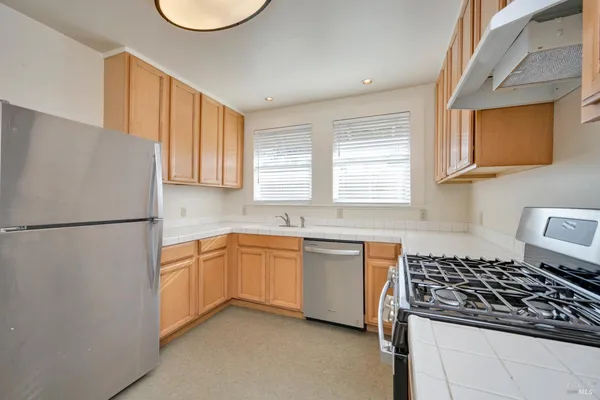 a kitchen with stainless steel appliances granite countertop a refrigerator stove sink and cabinets