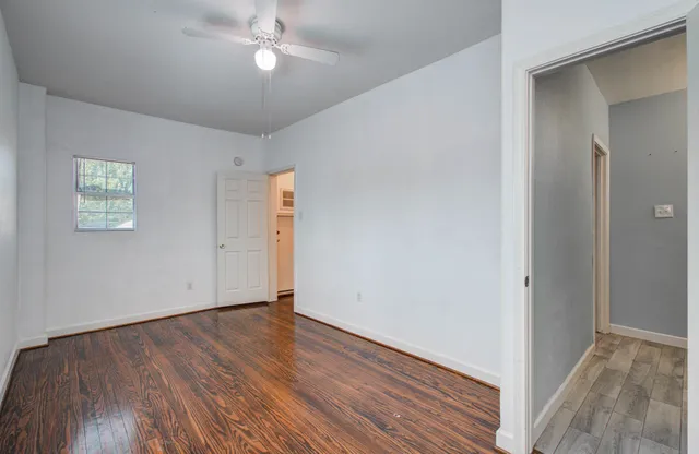 an empty room with wooden floor closet and windows