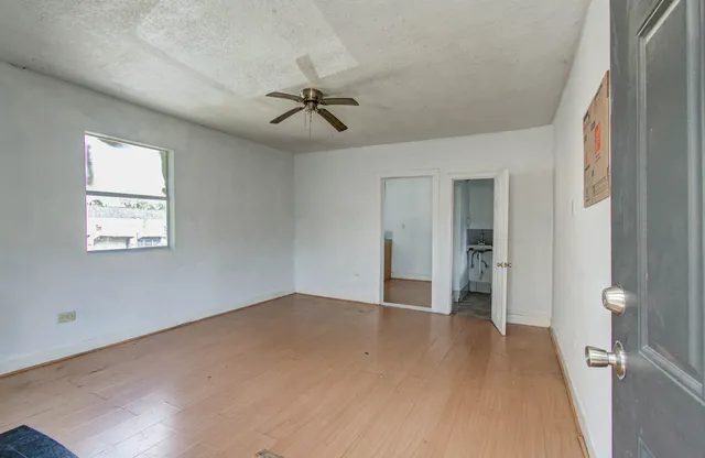 a view of empty room with wooden floor and fan