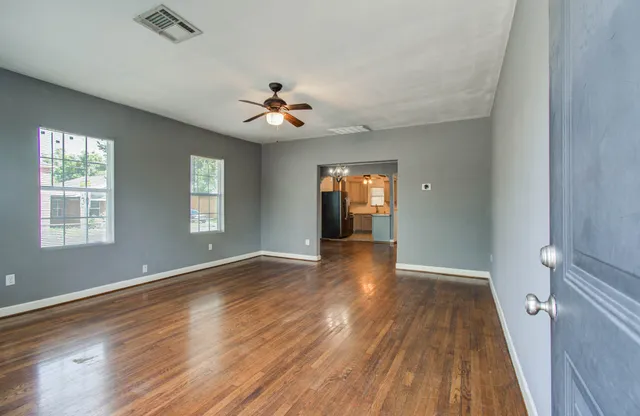 a view of empty room with wooden floor and fan