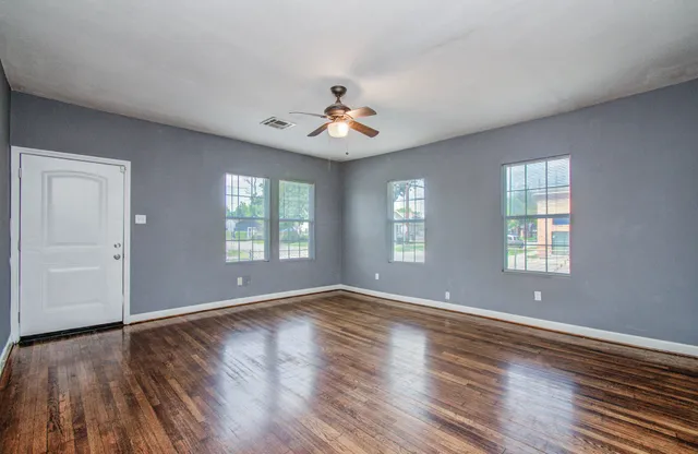 a view of an empty room with wooden floor and a window