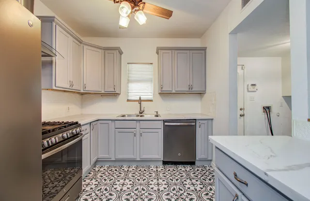 a kitchen with stainless steel appliances a sink a stove a refrigerator and cabinets