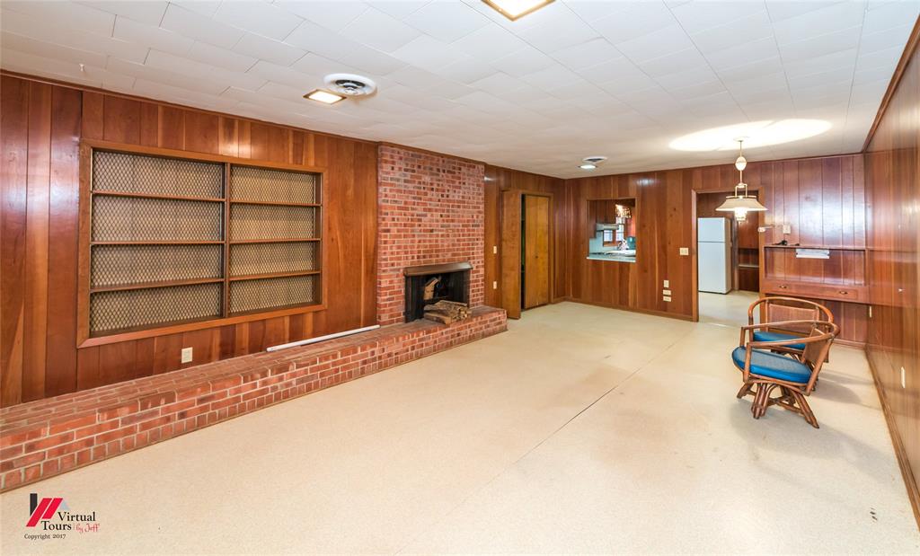 205 7th Street Northeast Springhill, LA 71075 - Photo 21 of 40 Brick fireplace with hearth, wood paneling, built-in shelving, built-in desk area, and recessed lighting