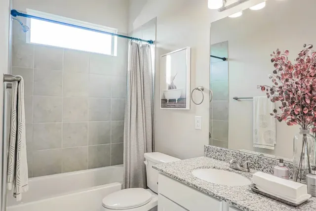a bathroom with a granite countertop sink toilet and shower