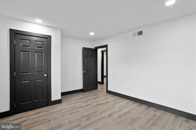 a view of an empty room with wooden floor and closet