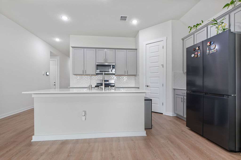 1813 Crow Hop View Leander, TX 78641 - Photo 20 of 33 a kitchen with stainless steel appliances a refrigerator sink and microwave