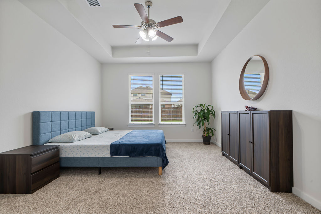 1813 Crow Hop View Leander, TX 78641 - Photo 21 of 33 a spacious bedroom with a bed a chandelier and a large window