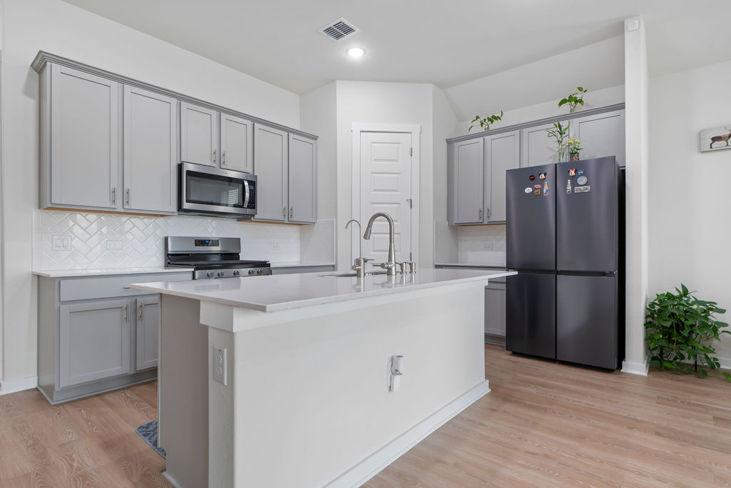 1813 Crow Hop View Leander, TX 78641 - Photo 4 of 33 a kitchen with stainless steel appliances a refrigerator sink and microwave