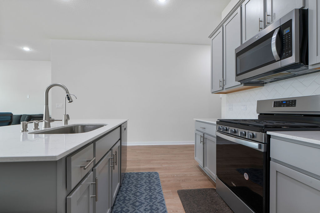 1813 Crow Hop View Leander, TX 78641 - Photo 7 of 33 a kitchen with stainless steel appliances a sink a stove and microwave