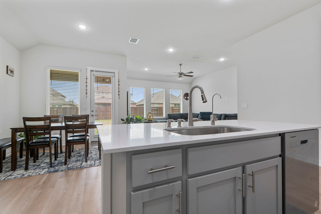1813 Crow Hop View Leander, TX 78641 - Photo 8 of 33 a dining hall with stainless steel appliances granite countertop a sink a stove a dining table and chairs with wooden floor