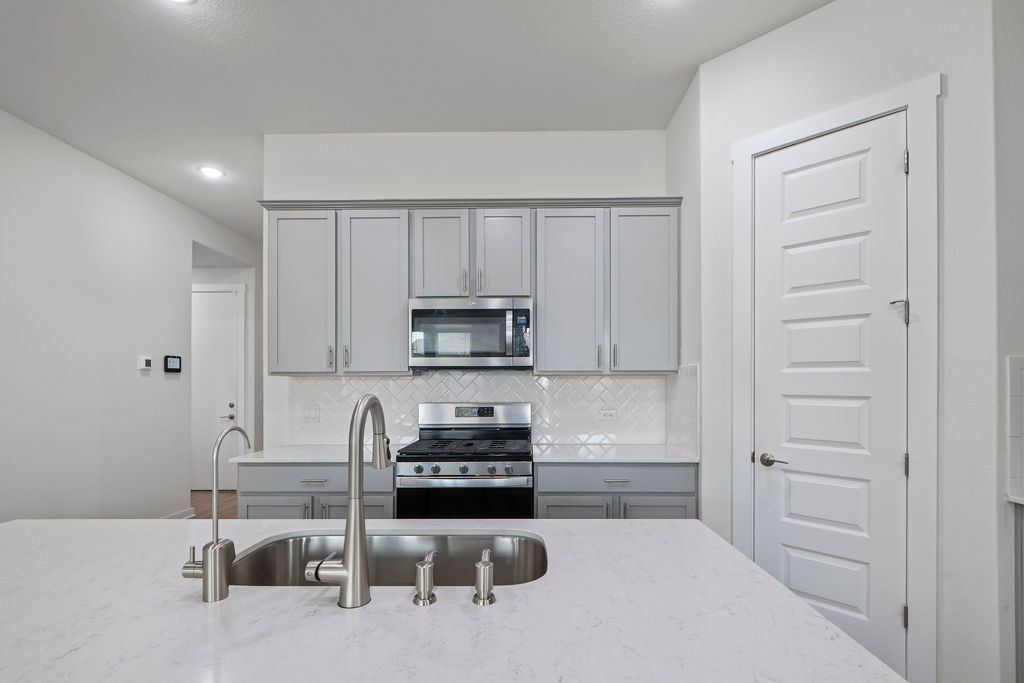 1813 Crow Hop View Leander, TX 78641 - Photo 9 of 33 a kitchen with white cabinets and stainless steel appliances