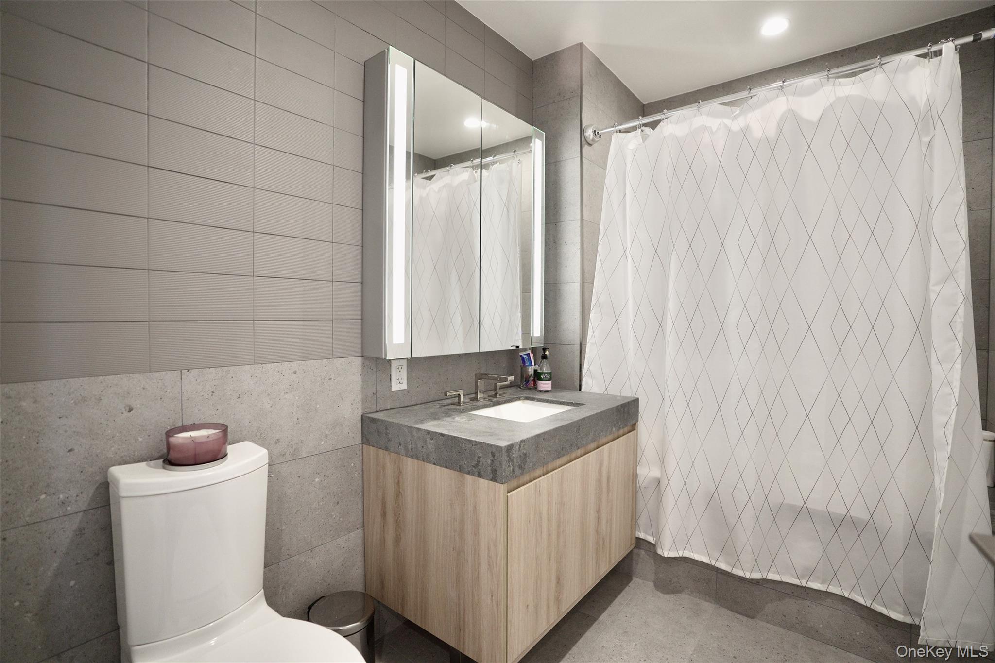 24-16 Queens Plaza South, Unit 2D Queens, NY 11101 - Photo 5 of 28 a bathroom with a granite countertop sink and a mirror