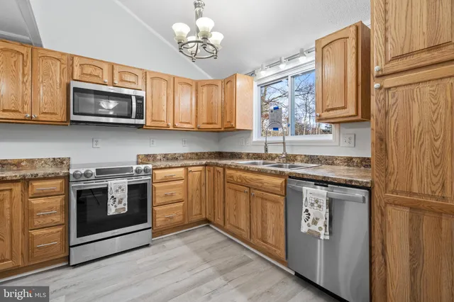 a kitchen with granite countertop stainless steel appliances a refrigerator stove top oven a sink and dishwasher