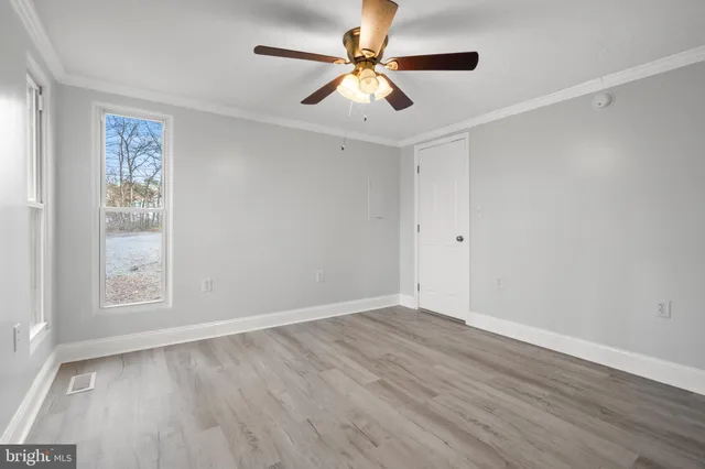 an empty room with wooden floor closet and fan chandelier fan