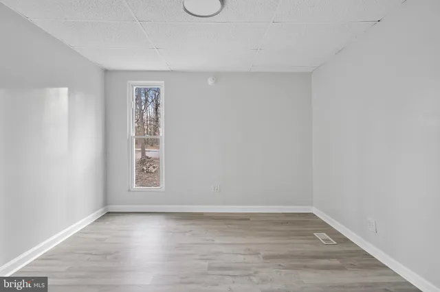 a view of empty room with wooden floor and floor to ceiling window
