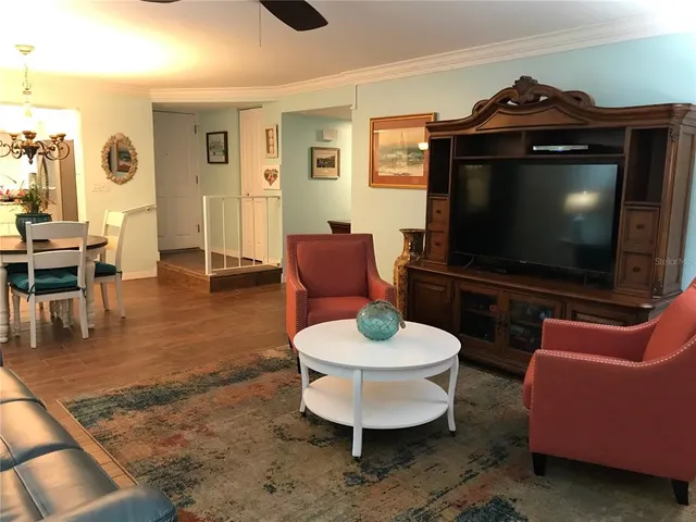 a living room with furniture a flat screen tv and kitchen view