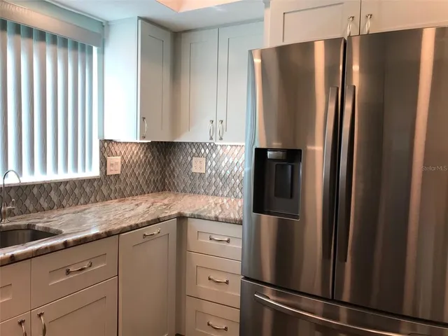 a kitchen with stainless steel appliances granite countertop a refrigerator and a sink