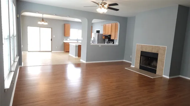an empty room with wooden floor a fireplace and windows
