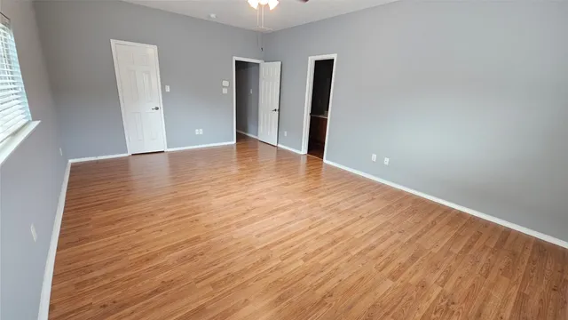 an empty room with wooden floor and windows
