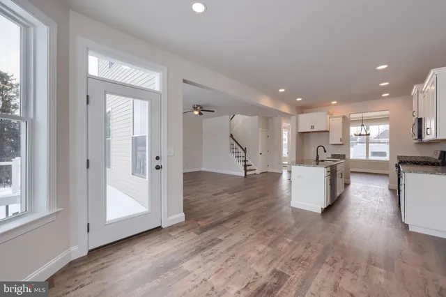 a view of kitchen with kitchen island wooden floors and stainless steel appliances