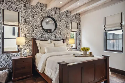 a bedroom with a bed and dresser with wooden floor