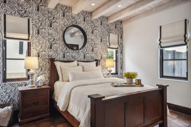 a bedroom with a bed and dresser with wooden floor