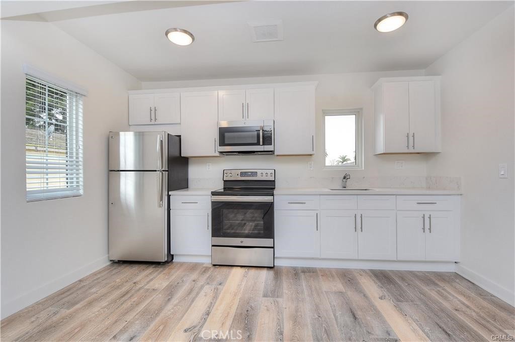 375 Termino Avenue, Unit A Long Beach, CA 90814 - Photo 5 of 13 a kitchen with a refrigerator stove and white cabinets